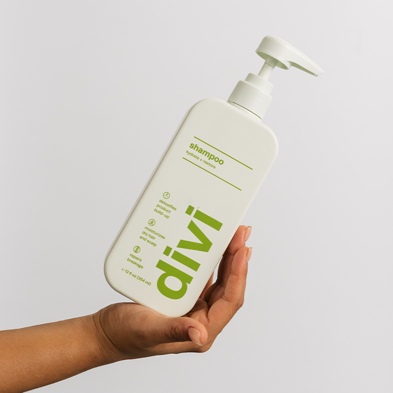 hand holding a light green bottle of divi shampoo