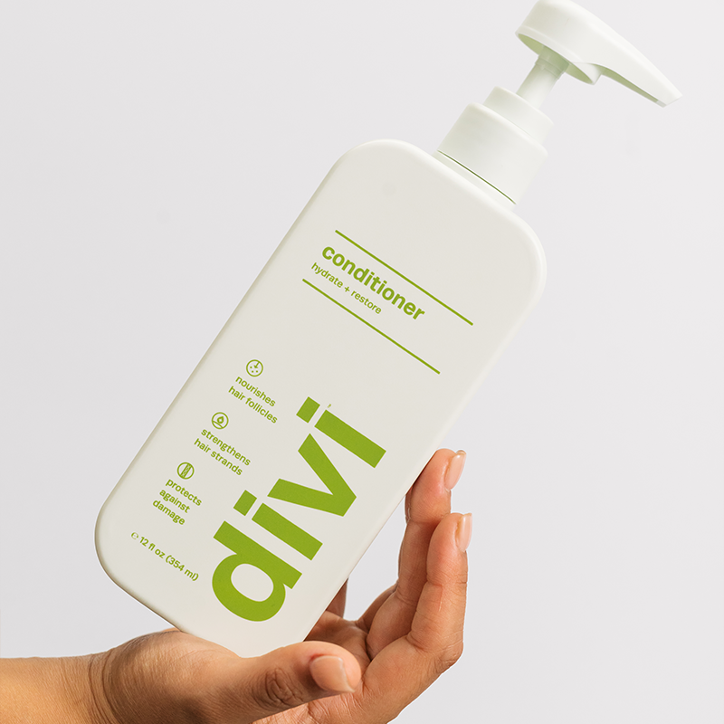 hand holding a light green bottle of divi conditioner