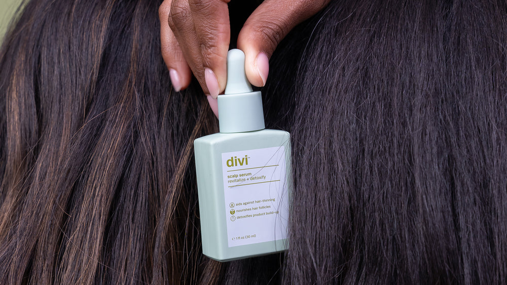 A lady holding a bottle of Divi scalp serum