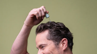 A man applying scalp serum to his scalp
