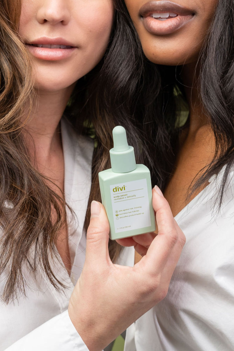 Two young ladies holding a bottle of Divi's Scalp Serum