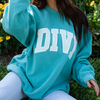 girl wearing divi crewneck sitting in grass