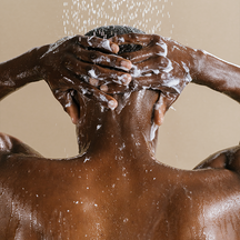 back view of man's washing his head with water and shampoo